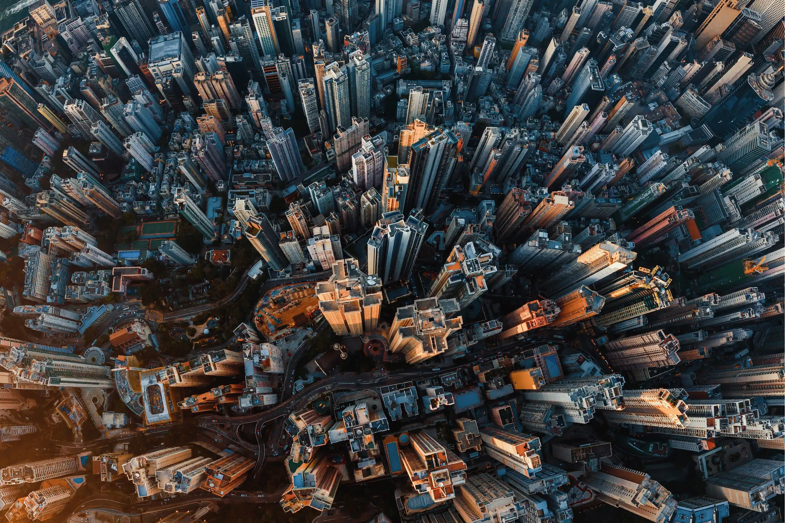 An aerial view at sunrise of a dense city rising above its harbour