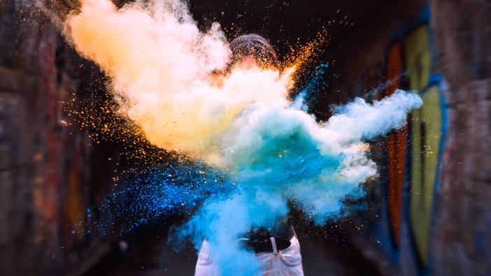 A burst of coloured powder against a dark alley wall
