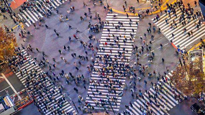 Crowds crossing a city intersection seen from directly above