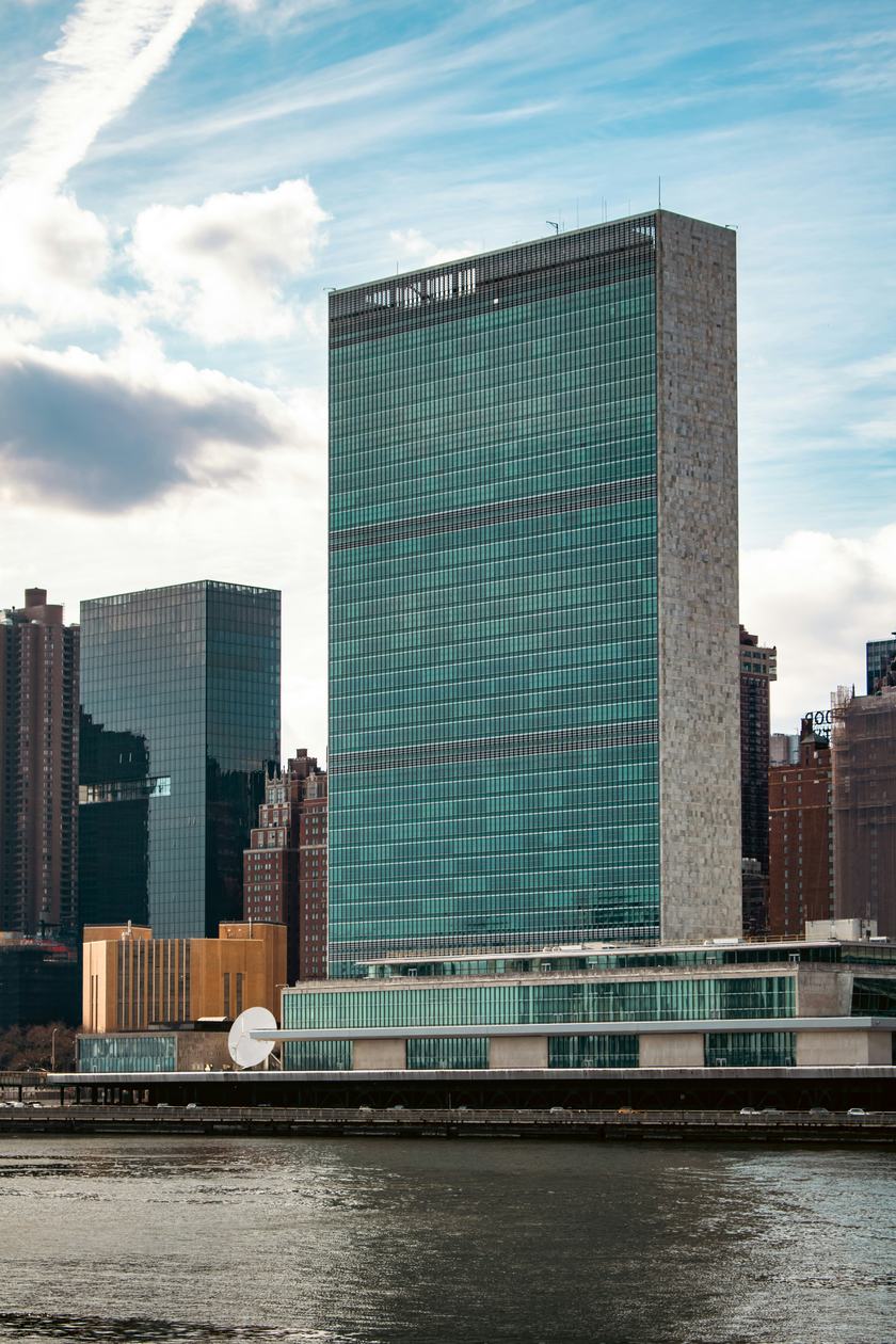 The United Nations Secretariat seen head-on across the East River under a blue sky